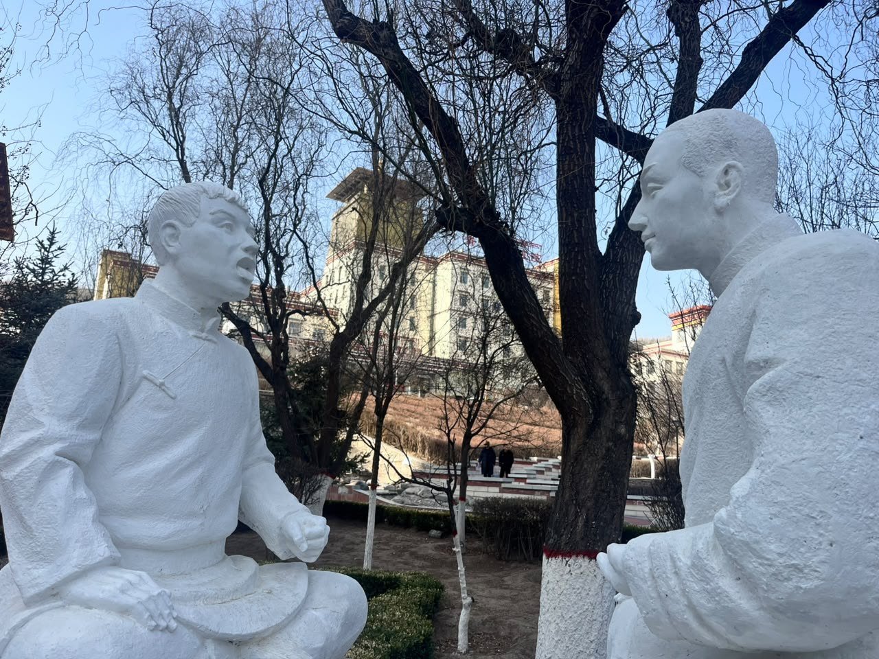 Duas esculturas sentadas frente a frente, em conversa, num jardim