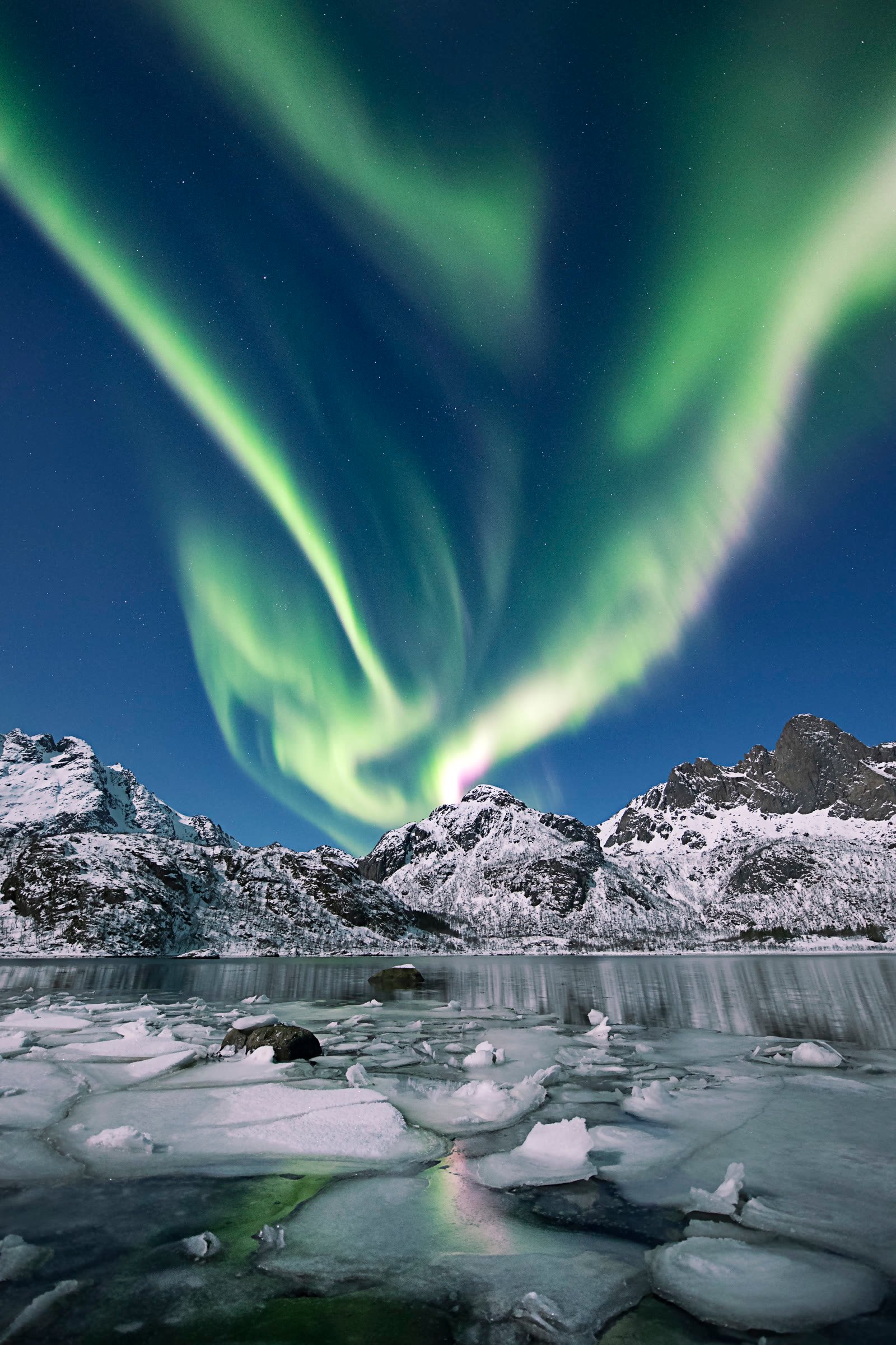 Aurora boreal sobre montanhas e agua congelada